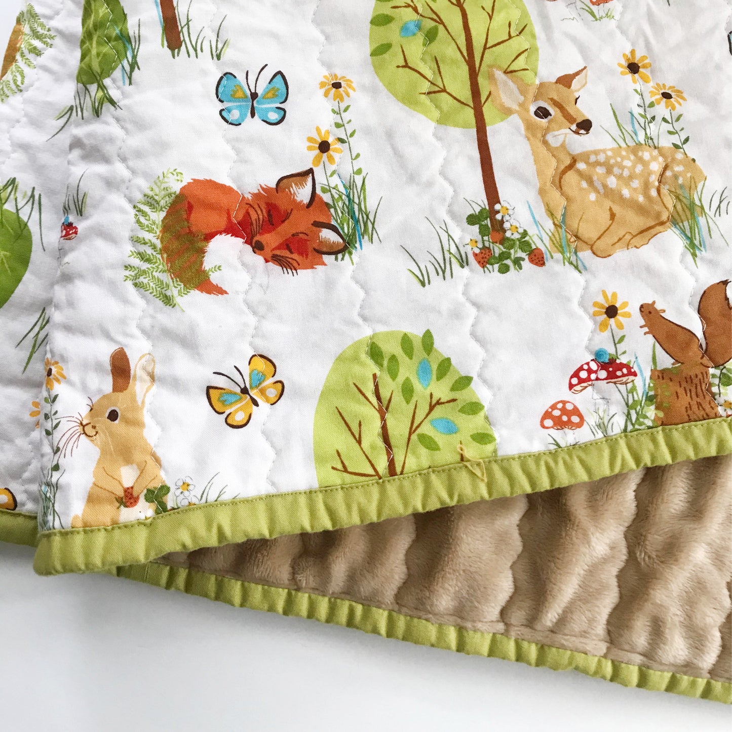 Forest animals on a white background, with brown minky and a sage green binding.